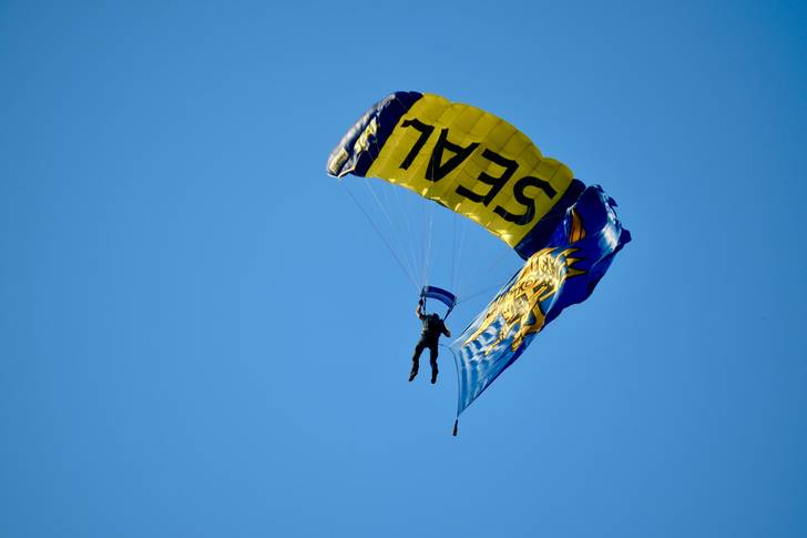A Navy Seal is seen with a parachute in the sky